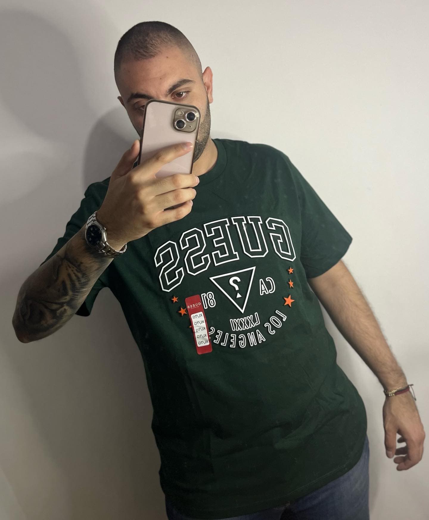 Camiseta Guess verde bosque de hombre con gráfico varsity CA 81 Los Angeles y estrellas naranjas, con etiqueta nueva, en modelo