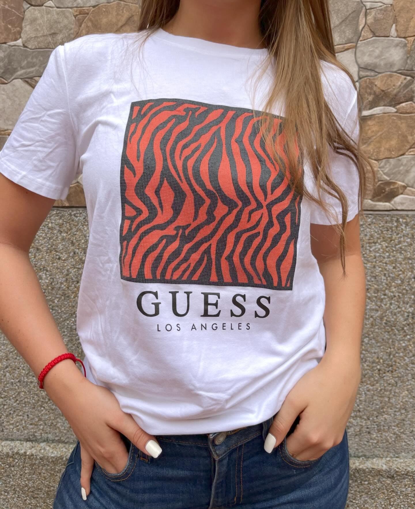 Camiseta Guess blanca de mujer con estampado zebra rojo y negro y letras Guess Los Angeles, puesta en modelo
