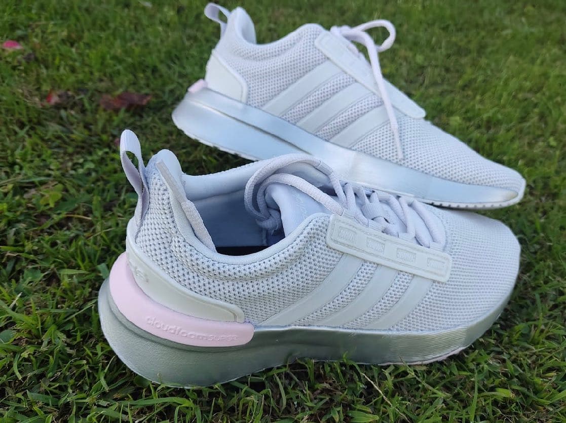Tenis adidas blancos de malla con detalle rosado en la suela, foto de producto sobre pasto
