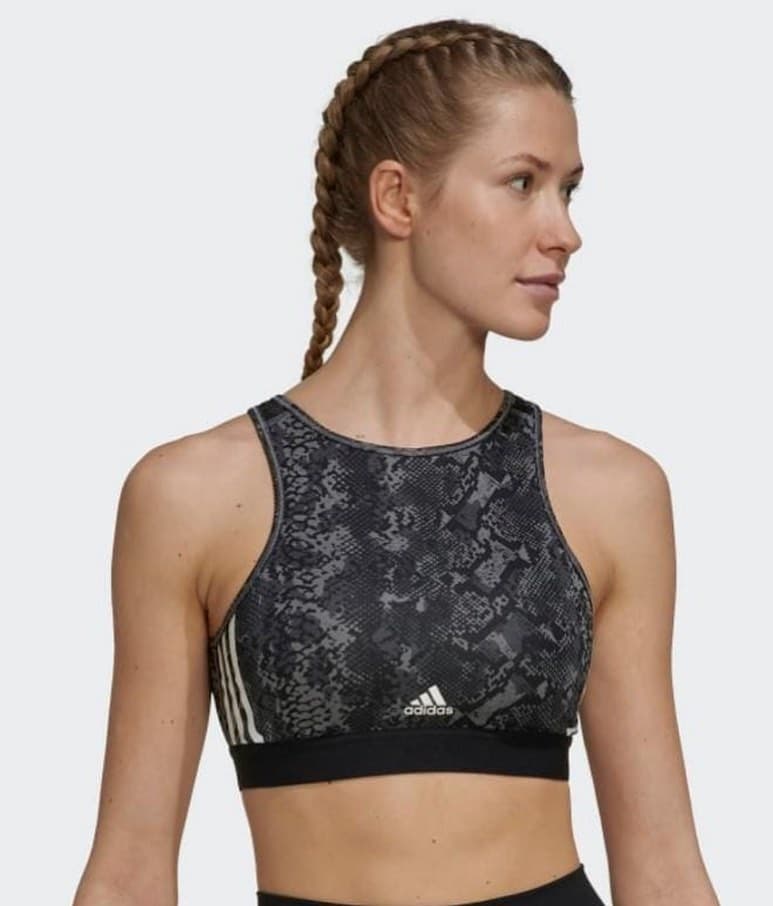 Top deportivo adidas de mujer con estampado de serpiente gris y negro, tres franjas blancas y banda elástica negra, en modelo